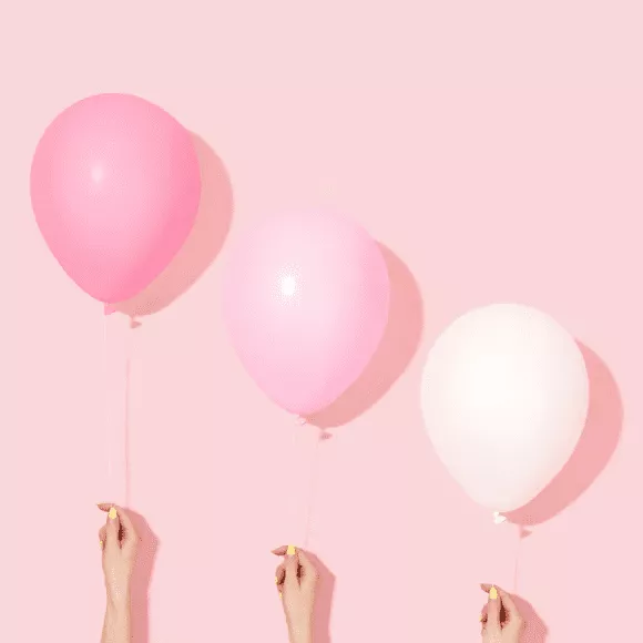 An example of an instagram ambassador program with pink branding showing three feminine hands holding a pink to white gradient of balloons